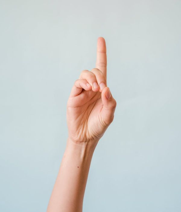 Person starting a simple yoga pose on a silver background.